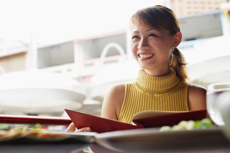 Woman in cafe, holding menu, looking away, low angle viewの写真素材
