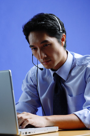 Man wearing headset, using laptopの写真素材