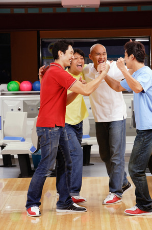 Four guys at a bowling alley, celebratingの写真素材