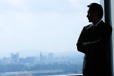 Businessman standing next to window, looking outの写真素材