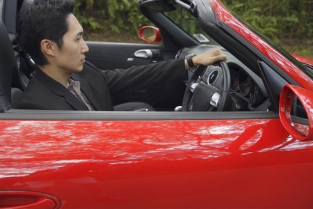 Man driving red convertible car