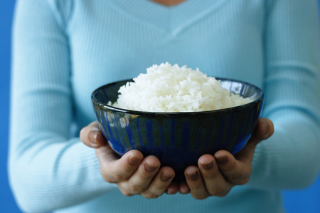 Woman holding bowl of rice, cropped imageの写真素材