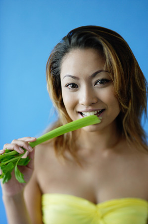 Woman looking at camera, eating celeryの写真素材