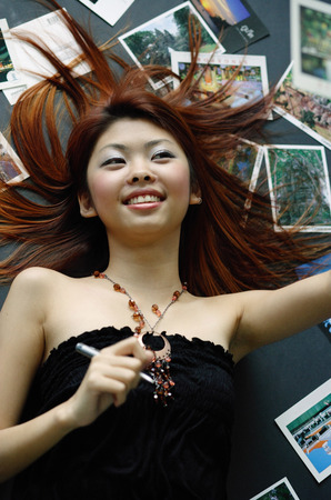 Woman lying on floor, postcards spread around herの写真素材