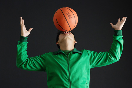 Young man balancing basketball on noseの写真素材