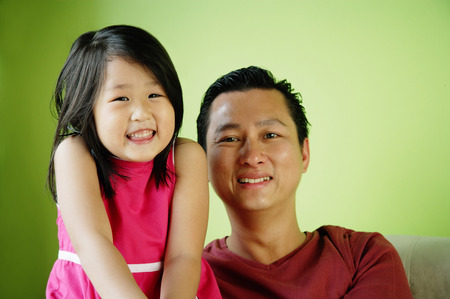 Father and daughter, side by side, smilingの写真素材