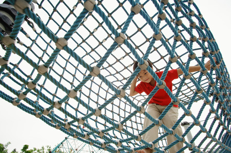 Young boy crawling through net tunnelの写真素材