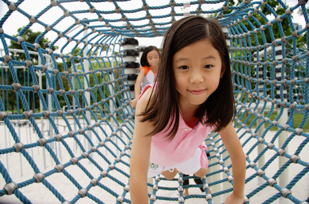 Girls at playground, going through net tunnelの写真素材