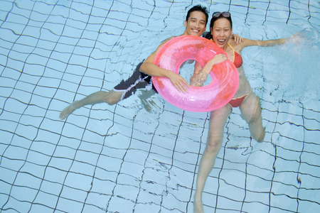 Couple in swimming pool holding on to inflatable ringの写真素材