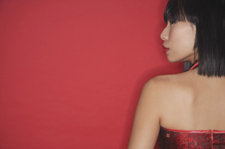 Woman against red background, rear viewの写真素材