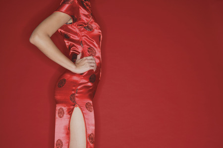Woman in cheongsam, hands on hips, croppedの写真素材