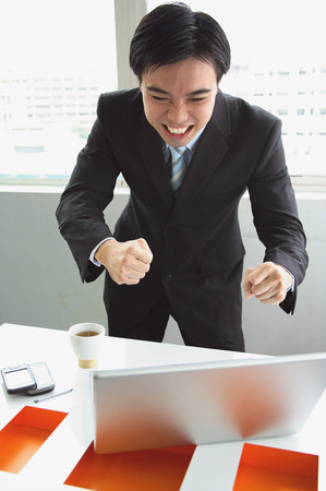 Businessman standing, looking at laptop, making a faceの写真素材