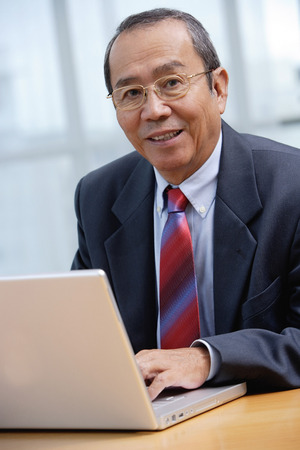 Businessman with laptop, smiling at cameraの写真素材