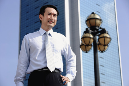 Businessman standing with hand on hip, looking awayの写真素材