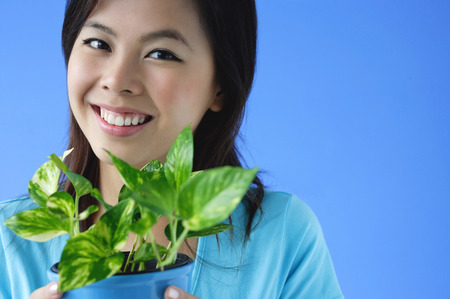 Young woman holding plant pot, portrait