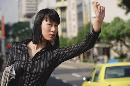 Businesswoman hailing a taxiの写真素材