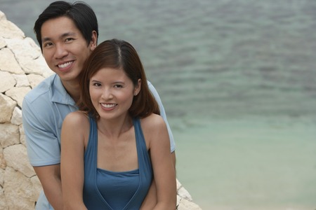 Couple looking at camera, sea behind themの写真素材