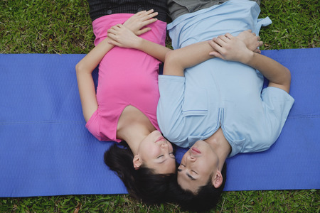 Couple in park, lying on mat, eyes closed