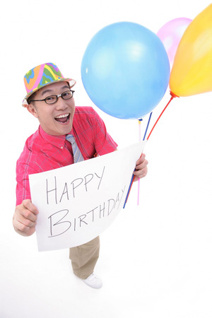 Man with party hat, holding balloons and a birthday greeting signの写真素材