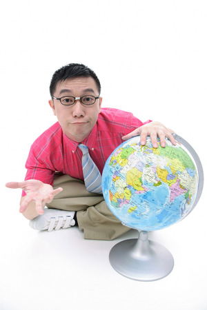 Man sitting on floor, hand on globe, shruggingの写真素材
