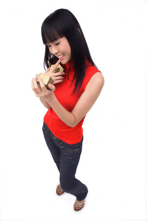 Young woman holding gift box, finger on mouthの写真素材