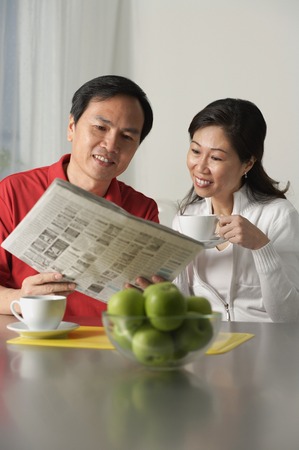 Mature couple looking at newspaper and having coffeeの写真素材
