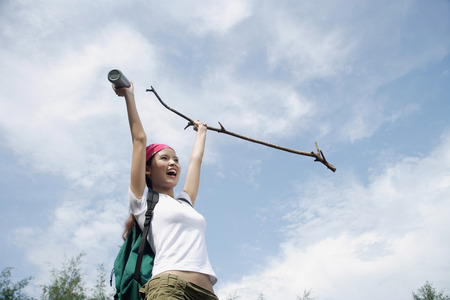 Female hiker, holding hiking stick in air, smilingの写真素材