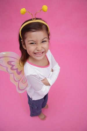 Young girl wearing fairy wings and deely bopper, arms crossed, smiling at cameraの写真素材