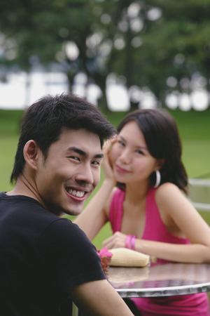 Man turning to smile at camera, woman in the backgroundの写真素材