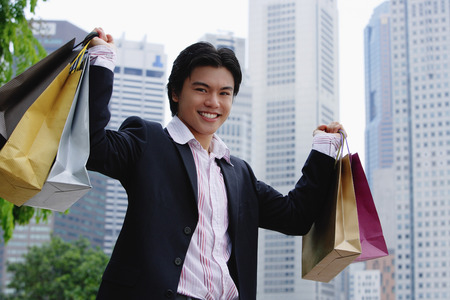 Man carrying shopping bags, smiling at cameraの写真素材