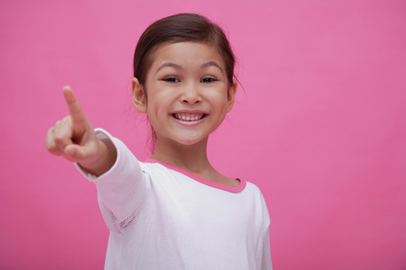 Girl smiling at camera, pointing a fingerの写真素材