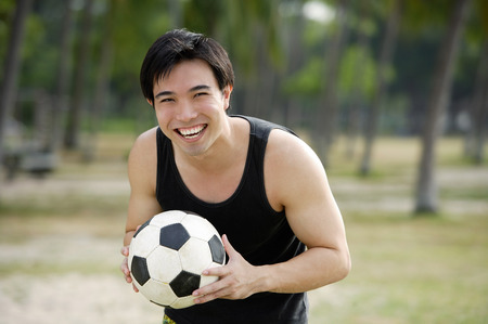 Man holding soccer ball, smilingの写真素材