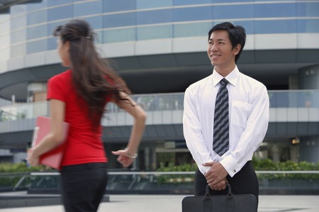 Male executive smiling at woman walking byの写真素材