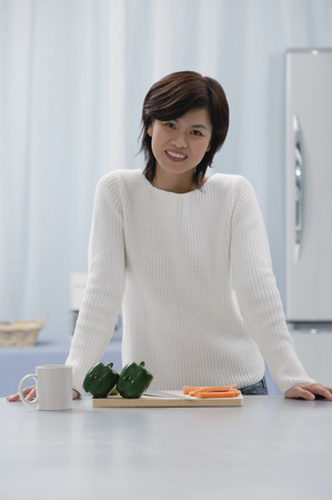 Woman in kitchen, smiling at cameraの写真素材