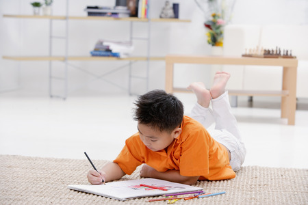 Boy lying on floor with sketch padの写真素材