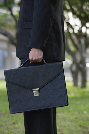 Businessman holding briefcase, side viewの写真素材