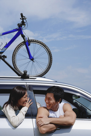 Couple sitting in car, bicycle on the roofの写真素材