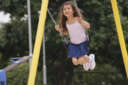 Girl on playground swingの写真素材