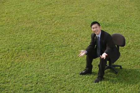 Businessman in office chair, smiling at cameraの写真素材