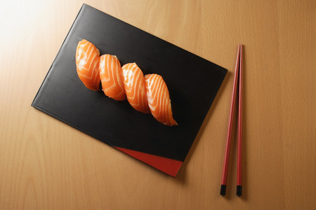 four pieces of salmon sushi, nigiri on rice ball, chopsticksの写真素材