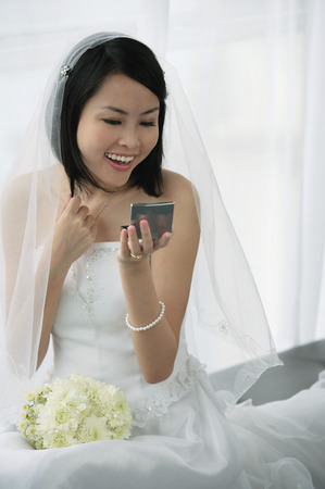 A bride does her makeup in the mirrorの写真素材