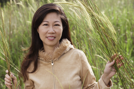 Woman in tall grass, nature, looking at camera, smilingの写真素材