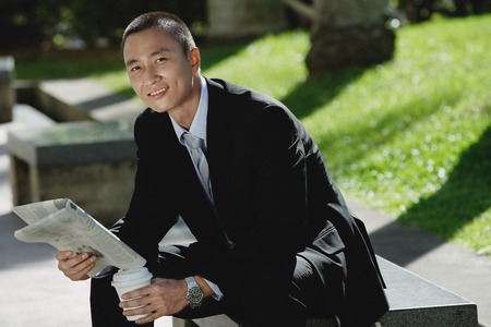 A man sits and reads the newspaper in the parkの写真素材