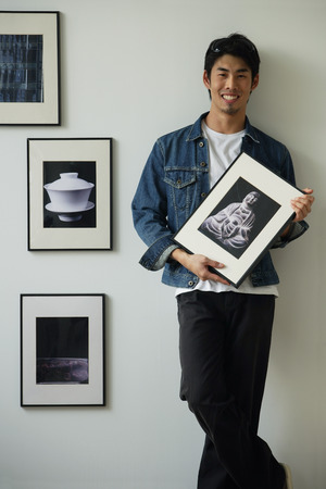 Young man holding framed photographsの写真素材