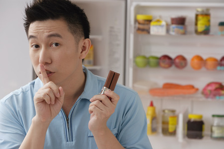 Man shushing while holding chocolateの写真素材