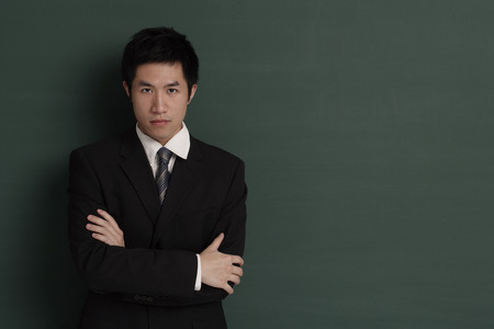 Businessman standing against black wall with arms crossedの写真素材