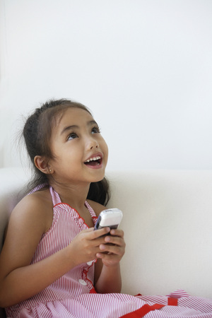 A young girl plays with a cellphoneの写真素材