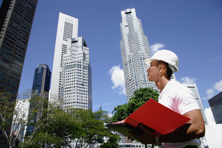 A man with a helmet stands in front of skyscrapersの写真素材
