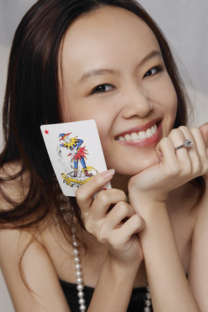 Young woman holding joker cardの写真素材