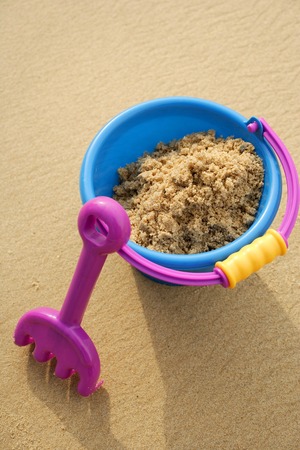 Beach Bucket filled with sand and shovel leaning against bucketの写真素材